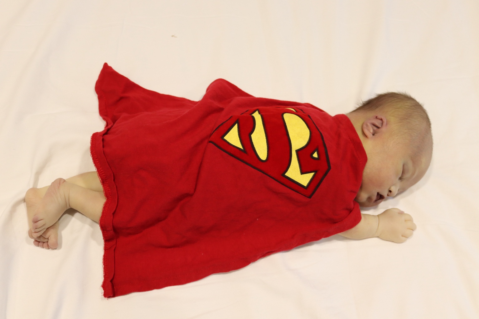 Benjamin Jett Romano as a baby, resting in a red superhero outfit